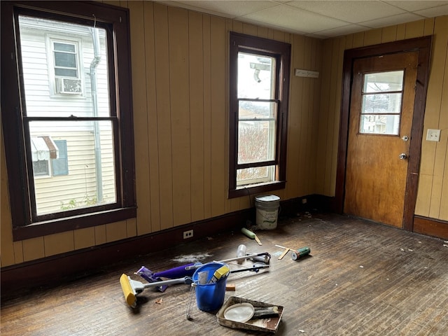 spare room with a drop ceiling and wooden walls