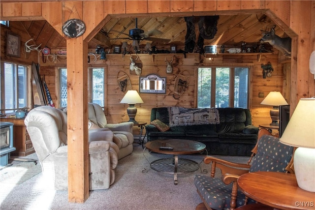 living room with ceiling fan, wooden walls, carpet, and vaulted ceiling