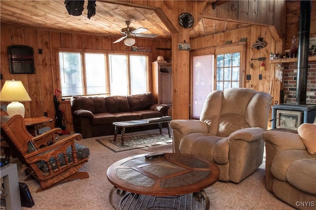 carpeted living room with ceiling fan, wood walls, a wealth of natural light, and vaulted ceiling