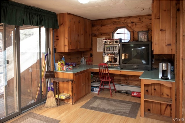 kitchen with wooden walls and light hardwood / wood-style flooring