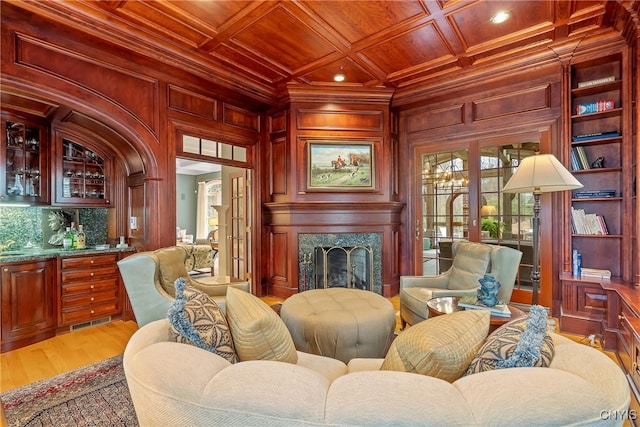 living room with light wood-type flooring, coffered ceiling, ornamental molding, wood ceiling, and a fireplace