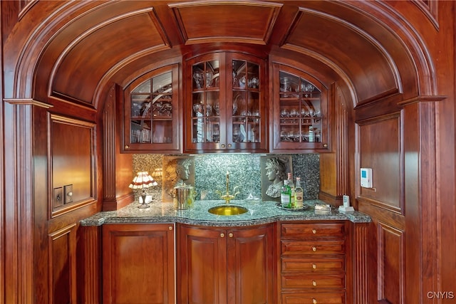 bar with lofted ceiling, sink, and stone counters