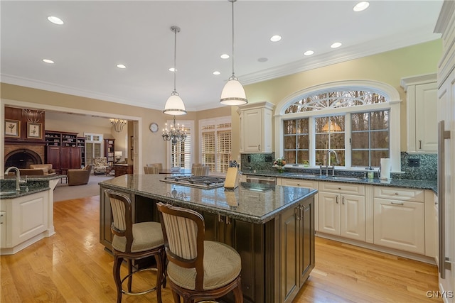 kitchen with a center island, decorative light fixtures, dark stone countertops, and sink