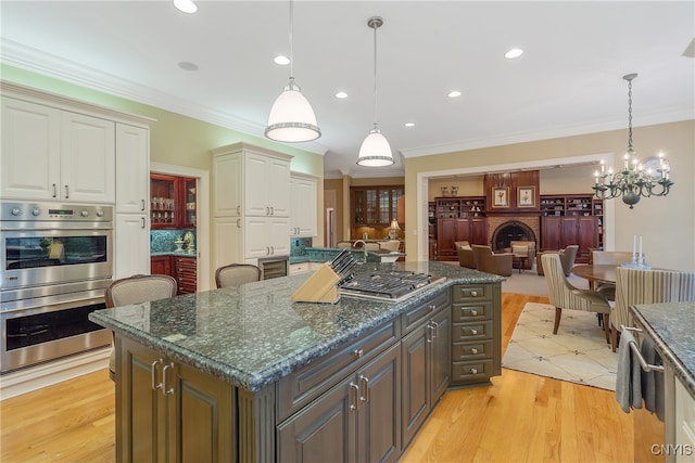 kitchen with a center island, light hardwood / wood-style flooring, decorative light fixtures, and appliances with stainless steel finishes