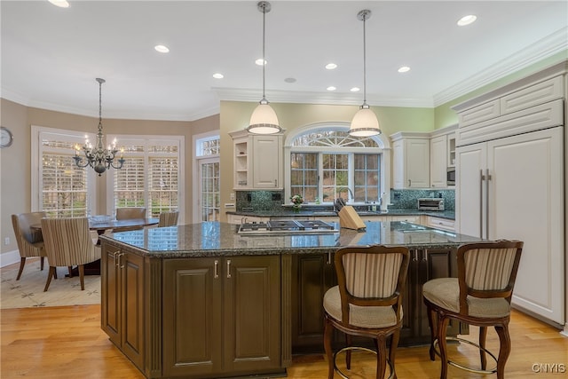 kitchen with tasteful backsplash, built in appliances, a center island, and light hardwood / wood-style flooring