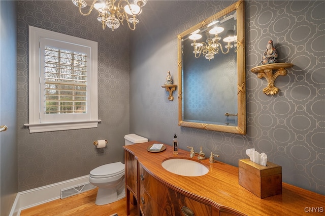 bathroom with vanity, wood-type flooring, a notable chandelier, and toilet