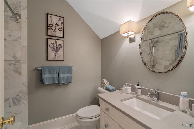 bathroom featuring vanity, toilet, lofted ceiling, and tiled shower