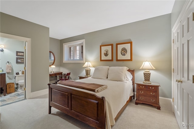 bedroom featuring light colored carpet and ensuite bathroom