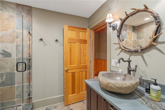 bathroom featuring a shower with door and vanity