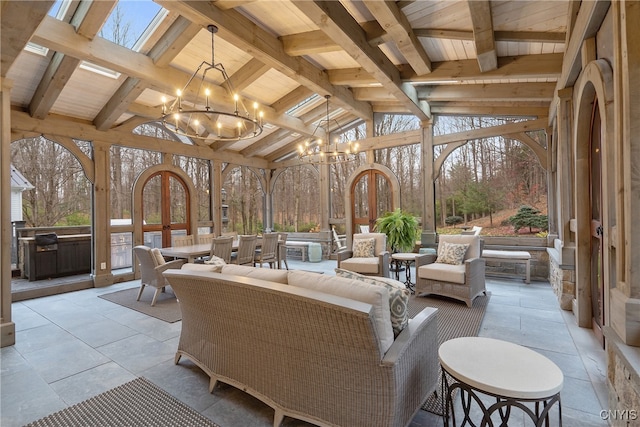 sunroom with lofted ceiling with skylight, french doors, and an inviting chandelier