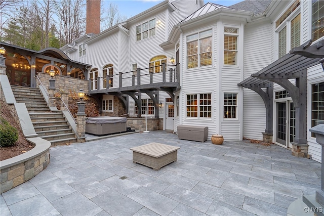 rear view of property with a patio and a hot tub