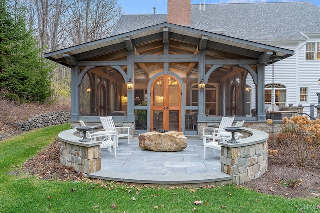 view of patio featuring a sunroom and an outdoor fire pit