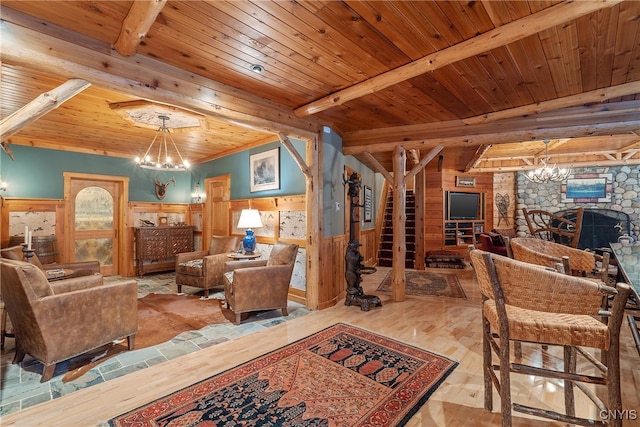 living room featuring a stone fireplace, light wood-type flooring, beamed ceiling, wood ceiling, and a chandelier