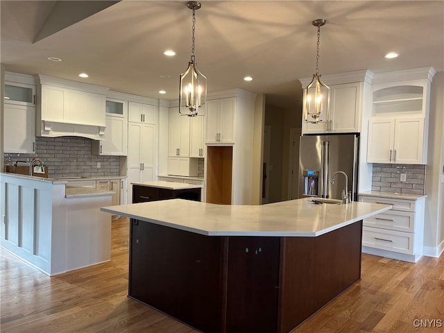 kitchen with a center island with sink, decorative light fixtures, white cabinets, and wood-type flooring