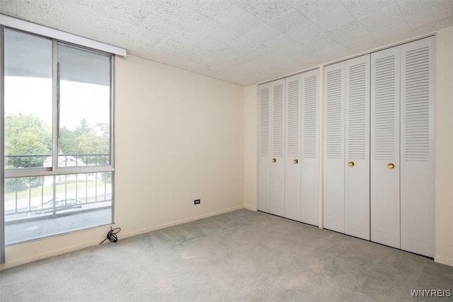 unfurnished bedroom with multiple closets and light colored carpet