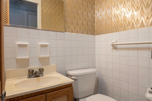 bathroom with vanity, toilet, and tile walls