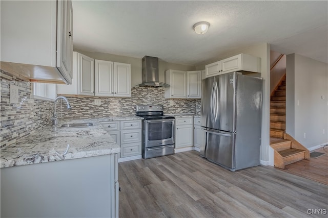 kitchen featuring wall chimney exhaust hood, stainless steel appliances, sink, light hardwood / wood-style floors, and white cabinetry