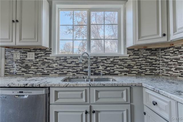 kitchen with stainless steel dishwasher, decorative backsplash, white cabinets, and sink