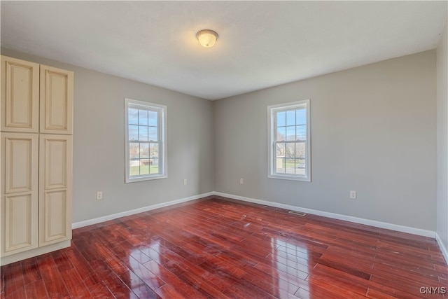 empty room with dark hardwood / wood-style floors and a wealth of natural light