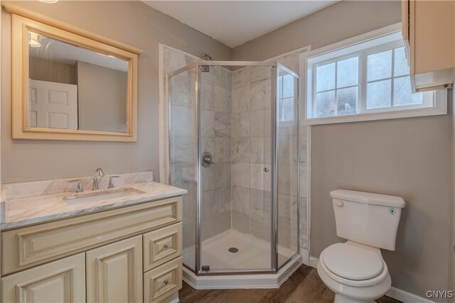 bathroom with wood-type flooring, vanity, toilet, and a shower with shower door