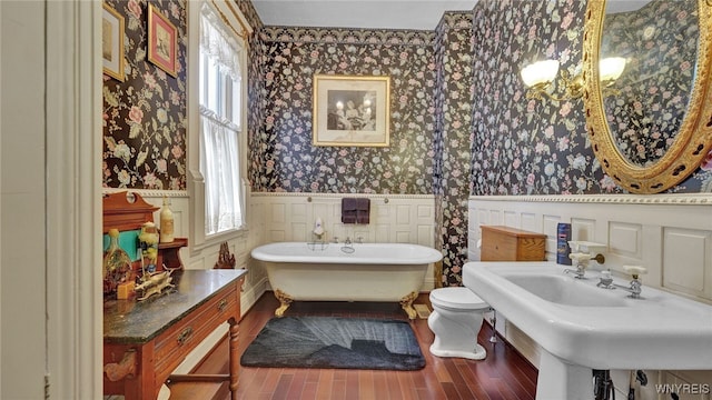 bathroom featuring a washtub, hardwood / wood-style flooring, toilet, and plenty of natural light