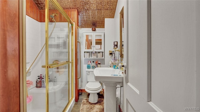 bathroom with tile patterned floors, toilet, and a shower with shower door