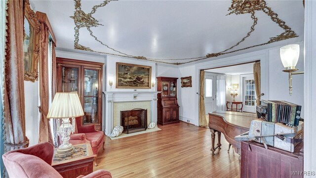 living room with light wood-type flooring, a wealth of natural light, and a brick fireplace