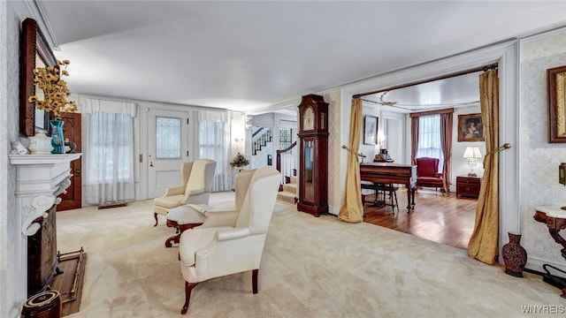 living area with crown molding and light colored carpet