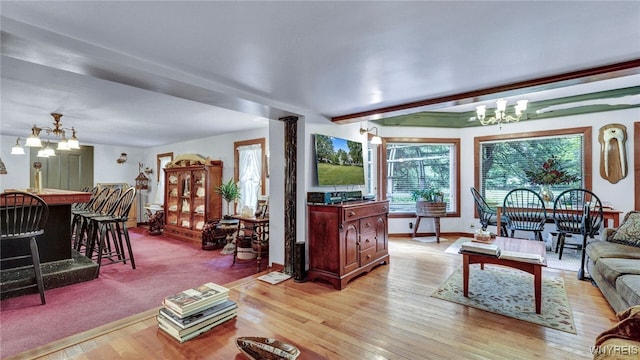 living room featuring ornate columns, light wood-type flooring, and a notable chandelier