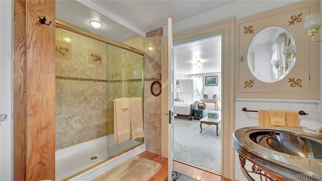 bathroom featuring wood-type flooring, an enclosed shower, and tile walls