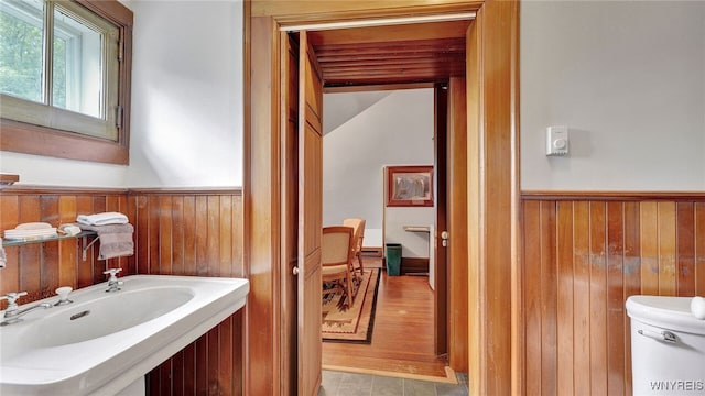 bathroom featuring hardwood / wood-style flooring, toilet, wood walls, and sink