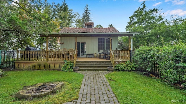 rear view of house featuring a yard, a fire pit, and a deck