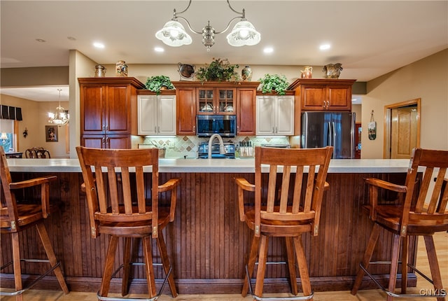 kitchen with a kitchen bar, stainless steel appliances, tasteful backsplash, and a notable chandelier