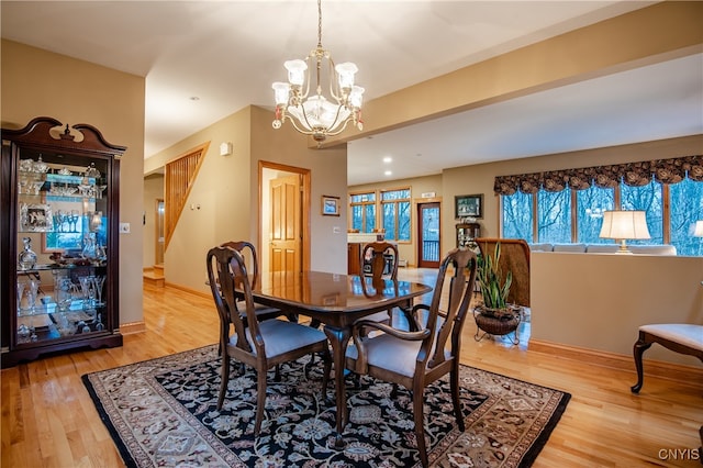 dining room with light wood-type flooring and an inviting chandelier