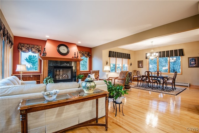 living room with hardwood / wood-style flooring, a notable chandelier, and a fireplace