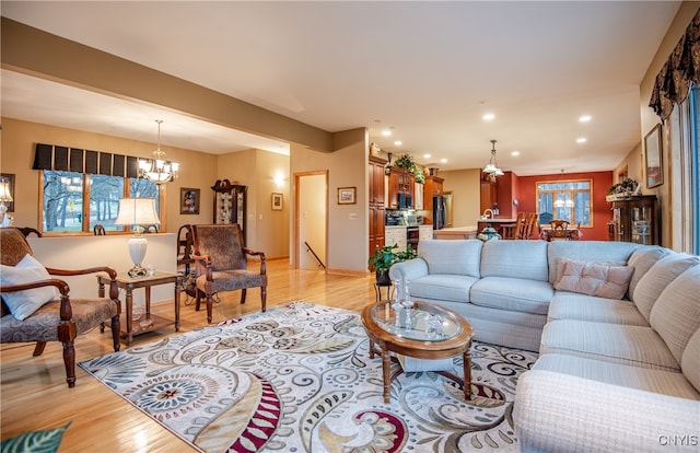 living room featuring a wealth of natural light, light hardwood / wood-style floors, and a notable chandelier