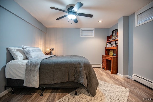 bedroom with hardwood / wood-style floors, ceiling fan, and a baseboard heating unit