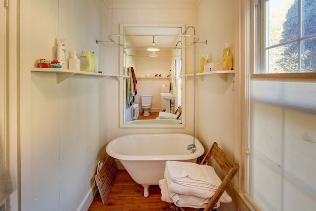 bathroom featuring hardwood / wood-style floors, toilet, and a bath