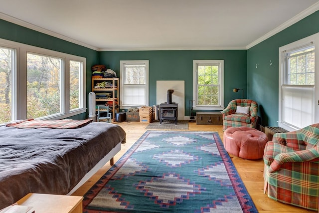 bedroom featuring a wood stove, light hardwood / wood-style flooring, and ornamental molding