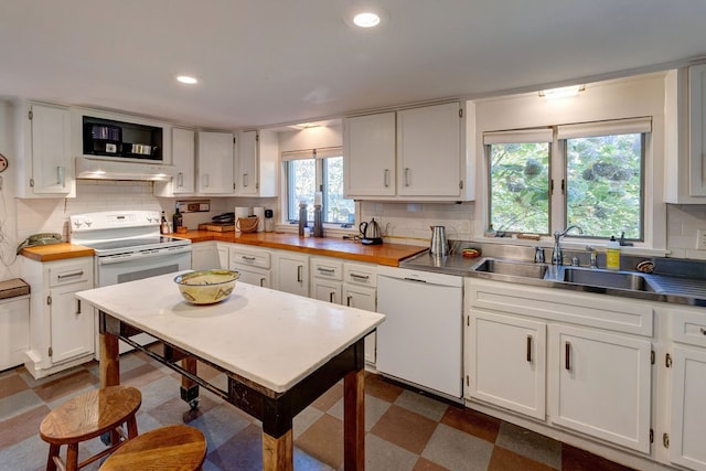 kitchen featuring a wealth of natural light, sink, white cabinets, and white appliances