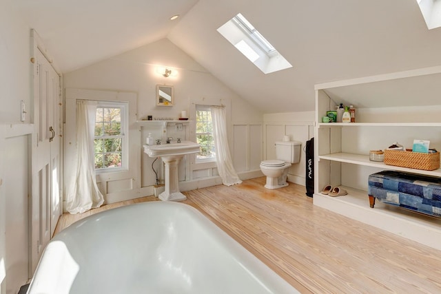 bathroom with hardwood / wood-style flooring, toilet, a healthy amount of sunlight, and vaulted ceiling with skylight