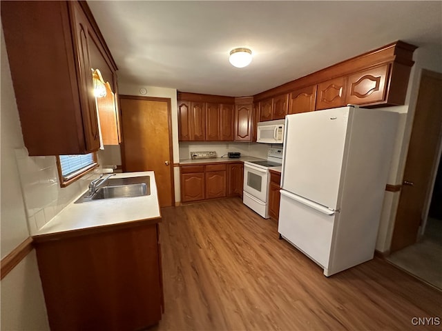 kitchen with white appliances, light hardwood / wood-style flooring, and sink