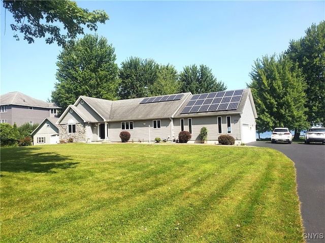 ranch-style home with a front yard, solar panels, and a garage