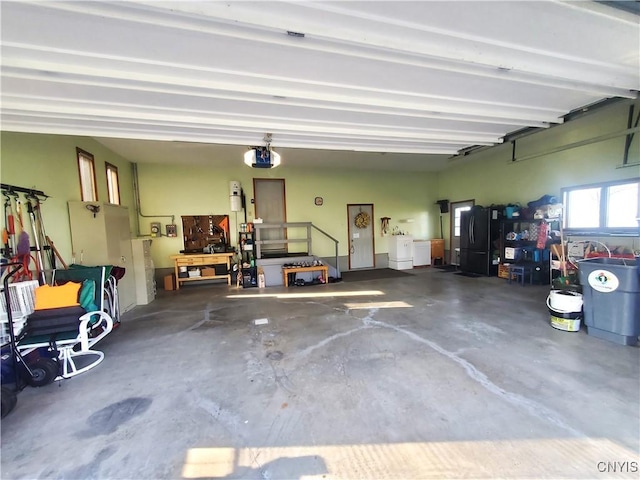 garage featuring a workshop area, black fridge, and a garage door opener