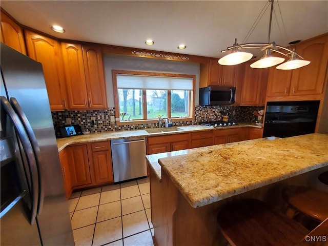 kitchen featuring appliances with stainless steel finishes, decorative light fixtures, tasteful backsplash, and sink