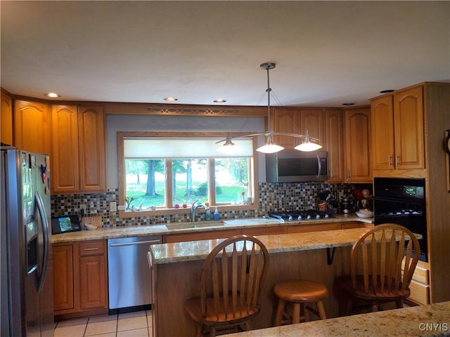 kitchen featuring light stone countertops, sink, decorative light fixtures, decorative backsplash, and appliances with stainless steel finishes