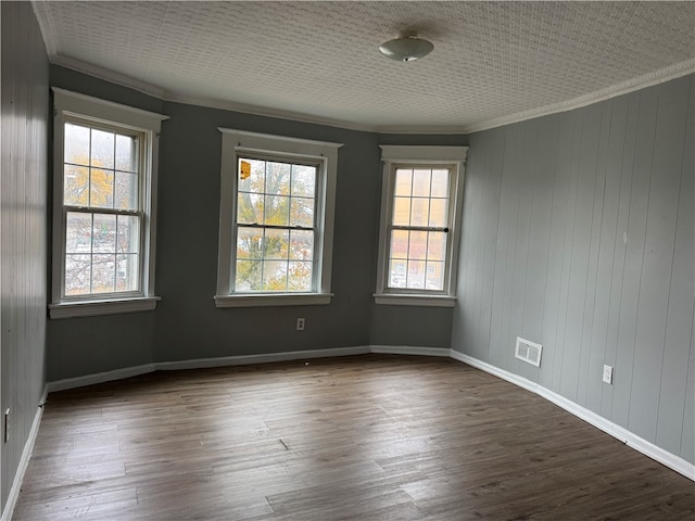 spare room featuring a wealth of natural light, dark hardwood / wood-style flooring, and ornamental molding