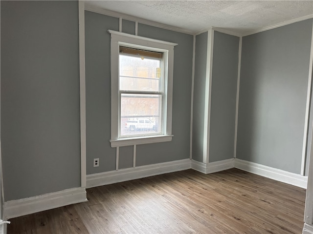 empty room featuring ornamental molding, a textured ceiling, and hardwood / wood-style flooring