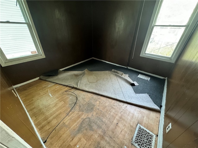 spare room featuring hardwood / wood-style flooring and wood walls