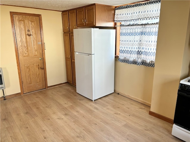 kitchen with light wood-type flooring, white appliances, and a textured ceiling